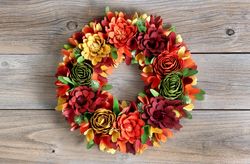 Colorful wreath made of wooden flowers and leaves on vintage wood