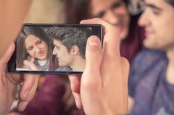 hands taking photos to couple on sofa
