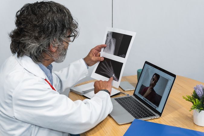 Older doctor using laptop and talking on video call