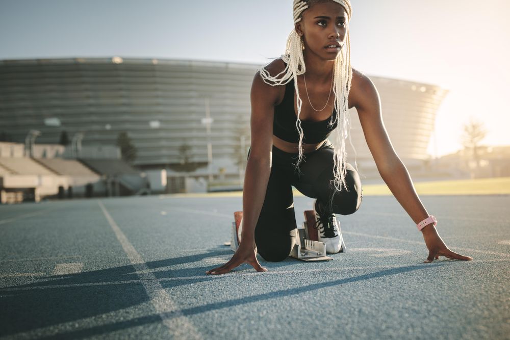 Female athlete taking position on her marks to start off the run