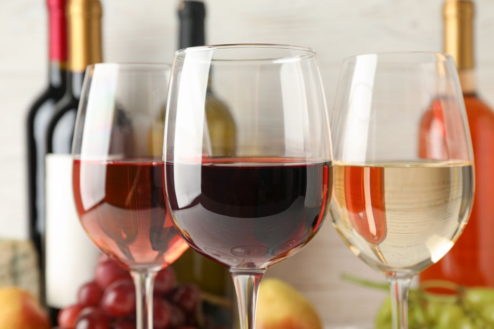 Grape, bottles and glasses with wine on blank background, close up