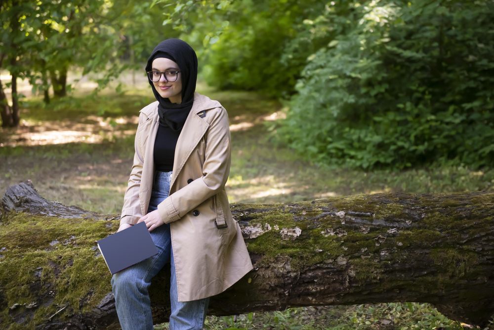 Woman relaxing on a mossy tree in a trench coat