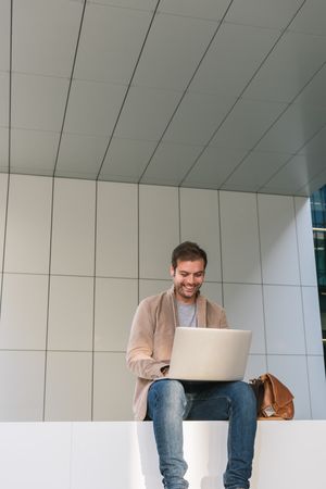 Cheerful businessman using laptop on street