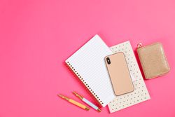 Stationery and smartphone on pink background, space for text
