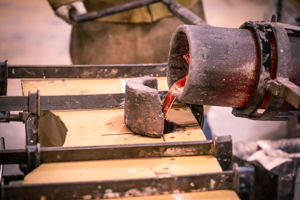 Man pouring heated metal from crucible in form