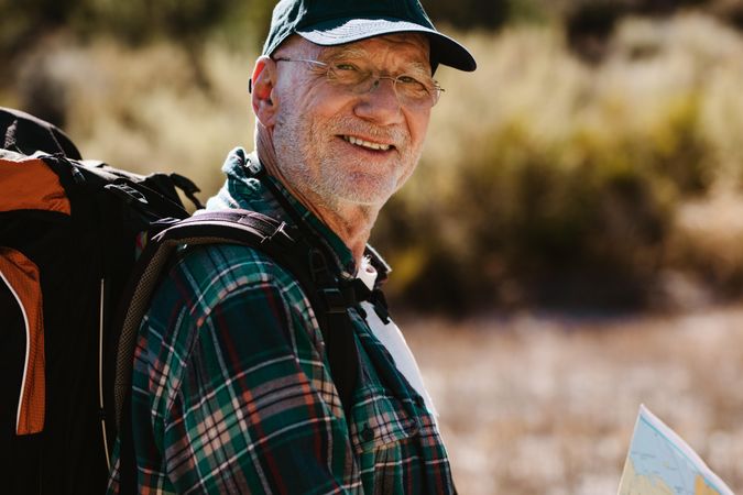 Older man carrying a backpack looking at camera and smiling