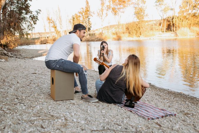 Young woman shooting friend playing guitar