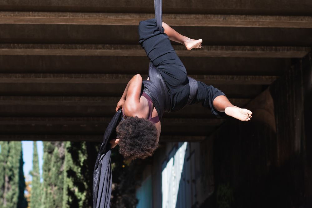Healthy woman doing aerial yoga in city