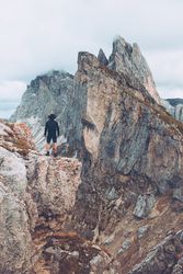 Back view of man standing on rock formation mountain in Dolomites, Italy
