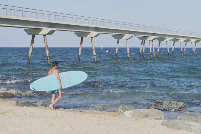 Male surfer holding surfboard approaching the sea