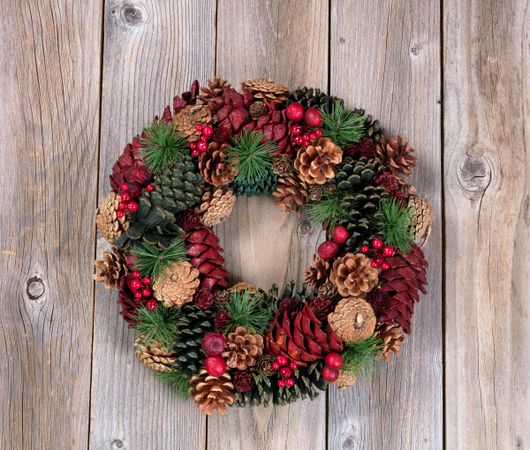 Holiday pine cone wreath on rustic wood