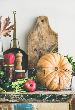 Fresh autumnal produce on kitchen counter, with squash and wooden board with apples