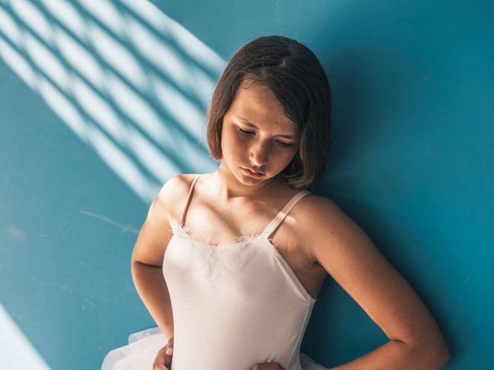 Ballerina standing with sad face near wall