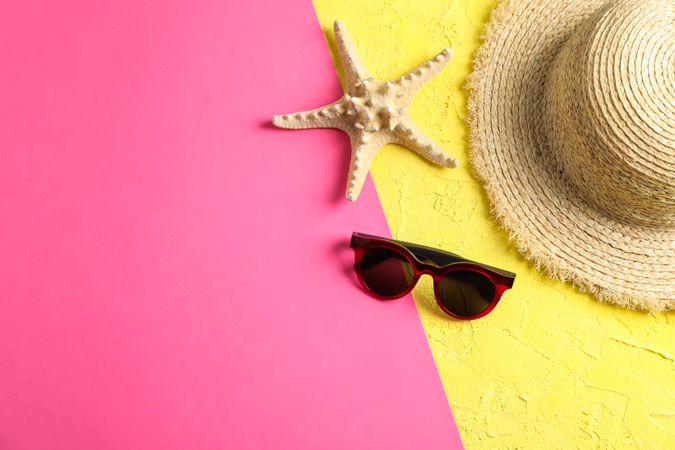 Composition with straw hat, sunglasses and starfish on two tone background, space for text