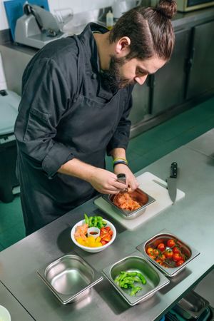 Chef preparing poke bowl with salmon and fresh vegetables in a restaurant kitchen