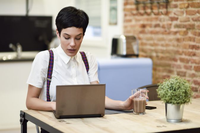 Woman in loft apartment concentrating on work on her laptop