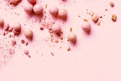 Powdered balls of pink makeup on pink background with copy space