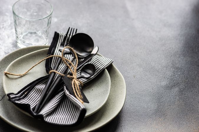 Table setting with dark cutlery & string on concrete background with copy space