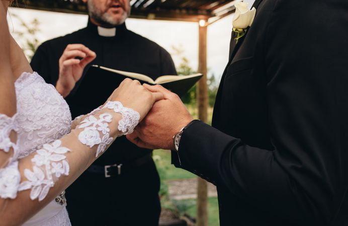 Priest performing a wedding ceremony for couple outdoors