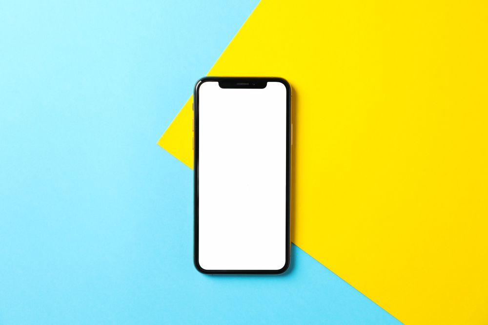 Phone with empty screen on two tone background, top view