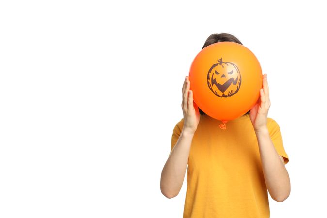 Woman holds Halloween balloon, isolated on plain background