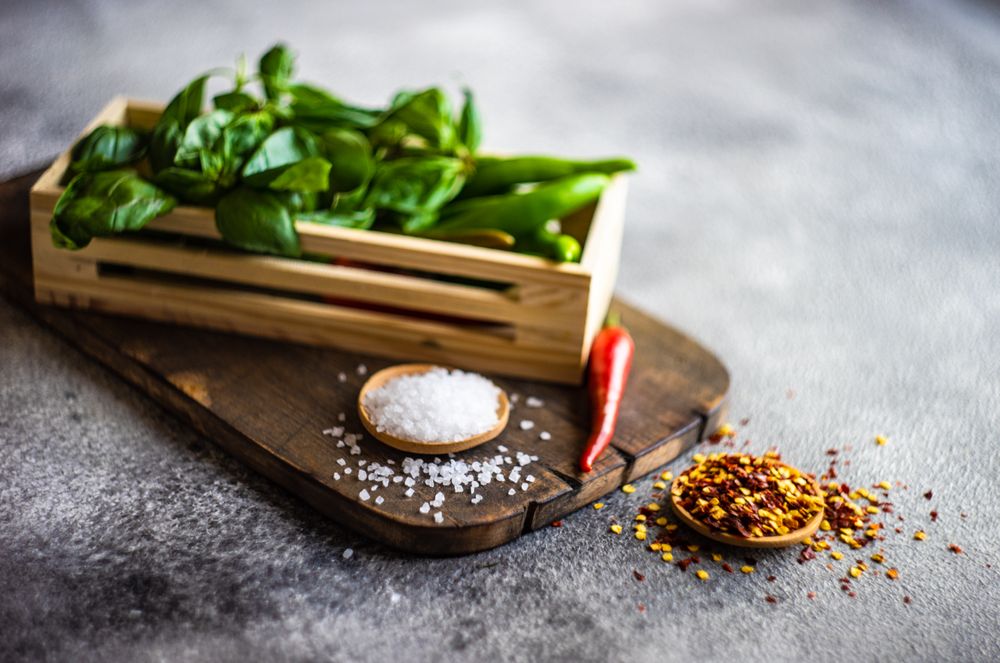 Peppers and basil in basket on cutting board