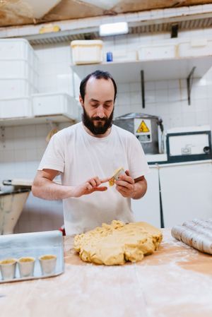 Bearded confectioner putting dough into cup