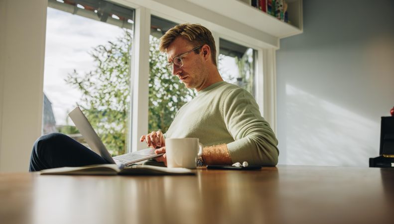 Busy male working from home in the morning with coffee cup on table