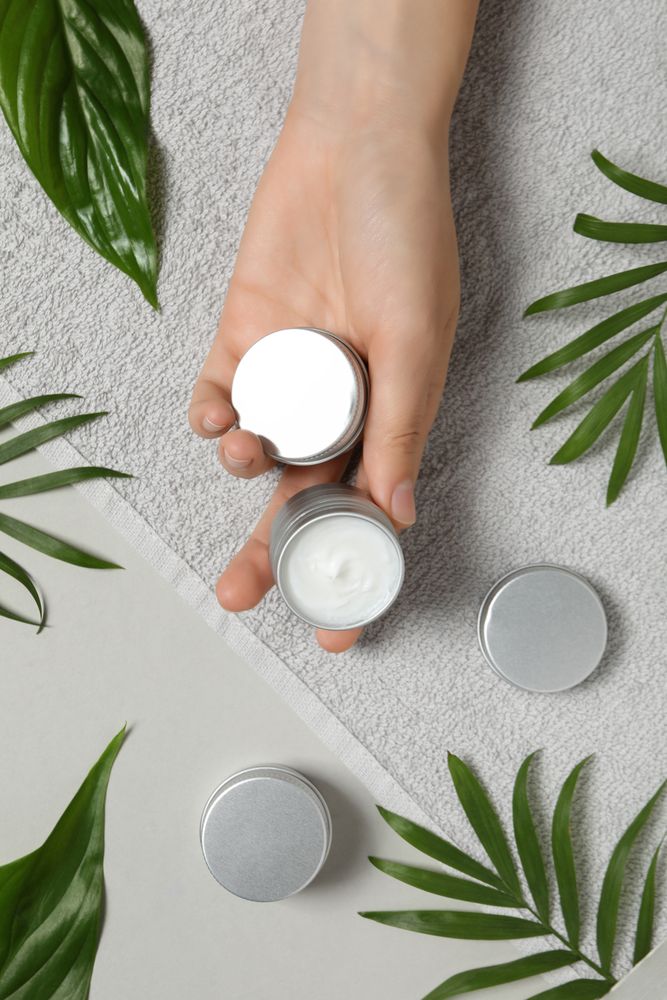 A jar of hand cream with leaves on a light background.