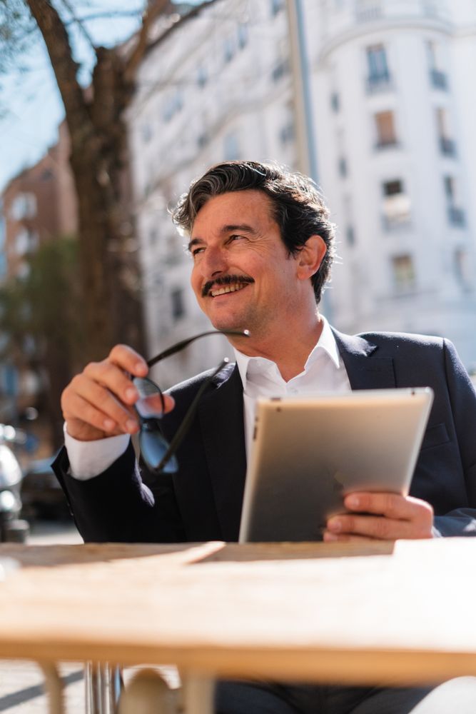 Mature man using gadget while relaxing at cafe