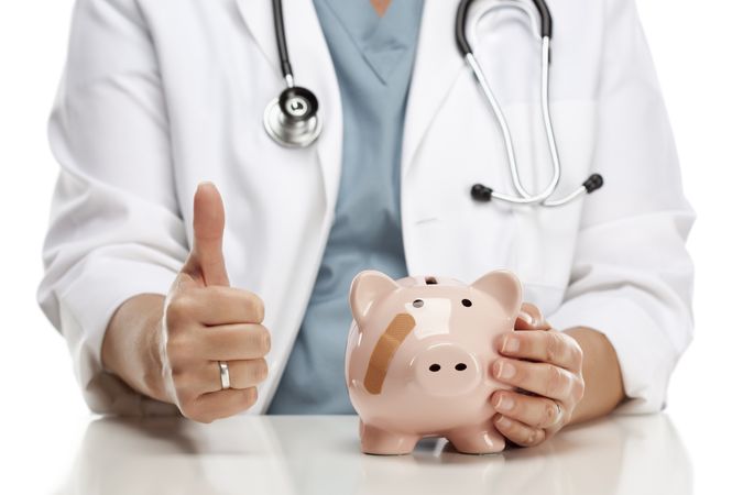 Doctor with Thumbs Up Holds Hand to Bandaged Piggy Bank