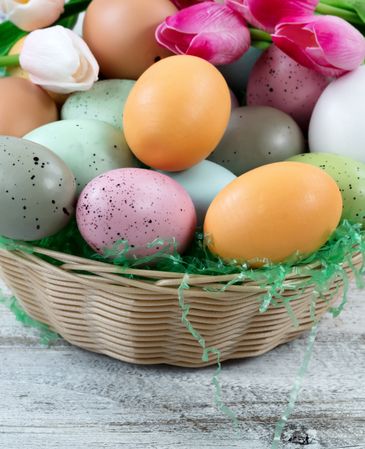 Basket of eggs and tulips for Easter holiday on rustic wood
