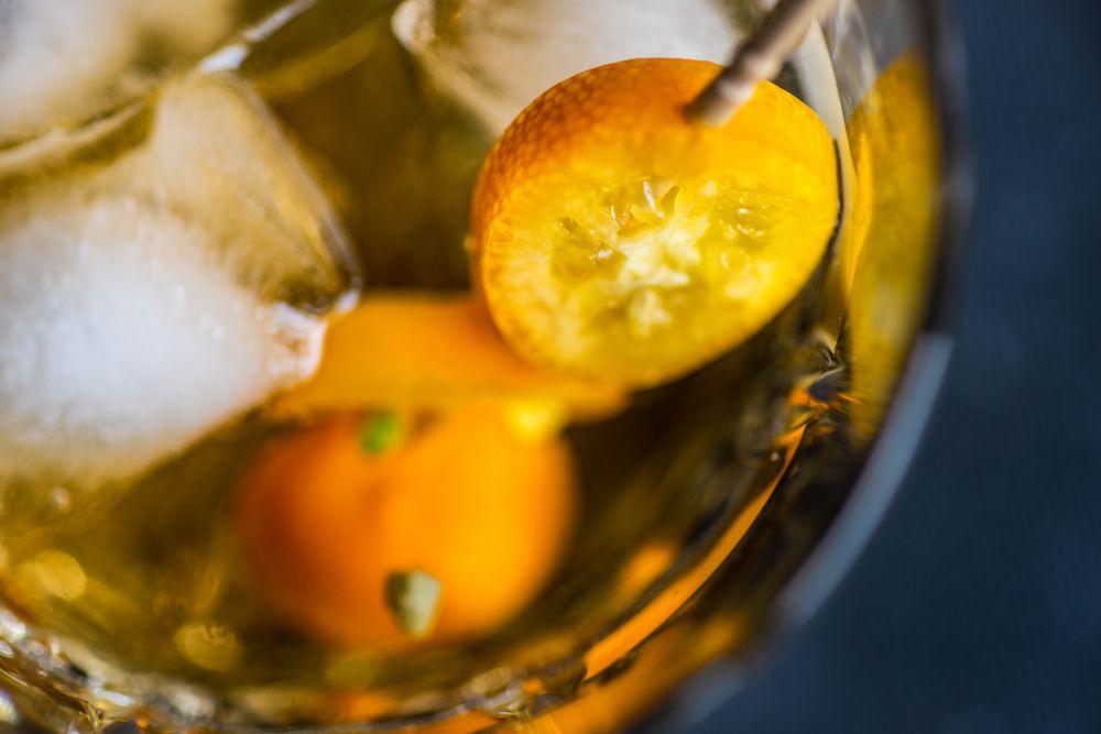 Whiskies on the rocks with slice of kumquat fruit