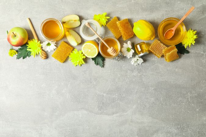 Flat lay with honey, flowers and fruits on grey background, copy space