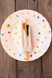 Ice cream on wooden stick with LGBTQIA symbol on decorated plate