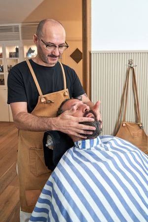 Professional barber treating male client