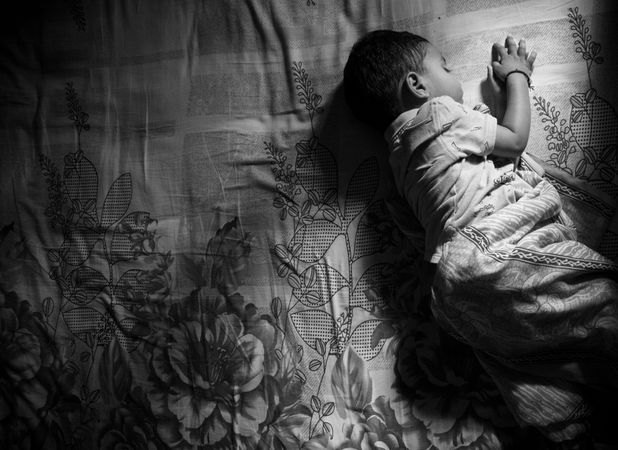Grayscale photo of toddler sleeping on bed