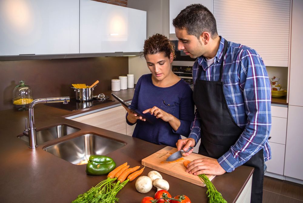 Couple checking digital tablet while prepping vegetables for dinner