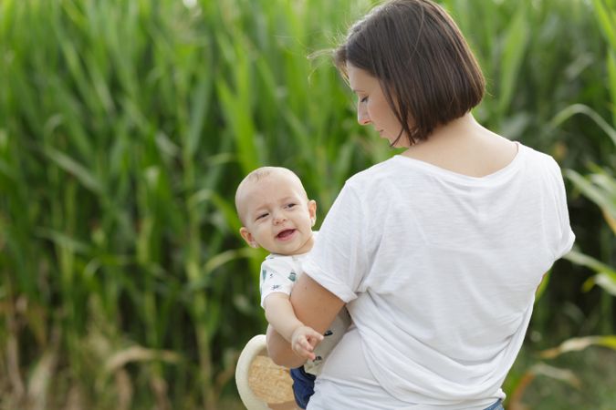 Adorable mother and child on hand enjoying and laughing in field