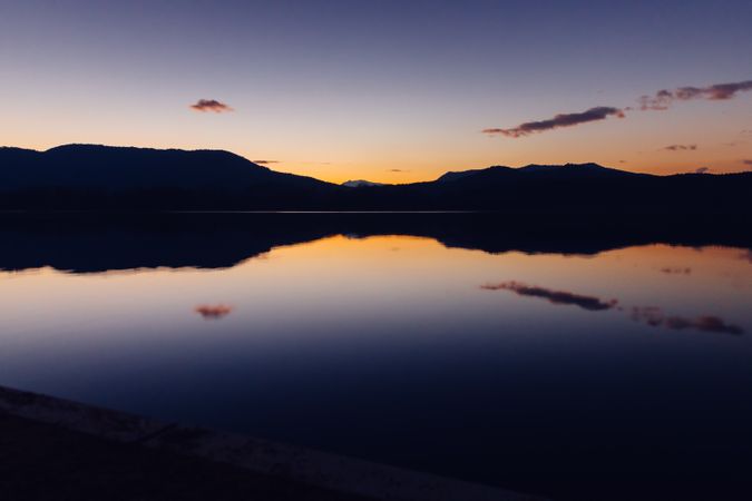 Sundown sky over mountains and calm water