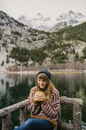 Woman on seat near wonderful lake between hills in snow