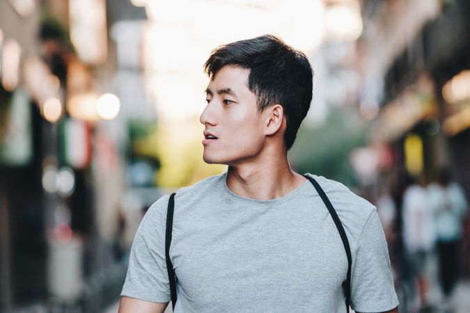 Confident Asian man walking along city street
