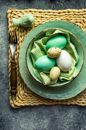 Bowl of pastel green decorative eggs on table setting
