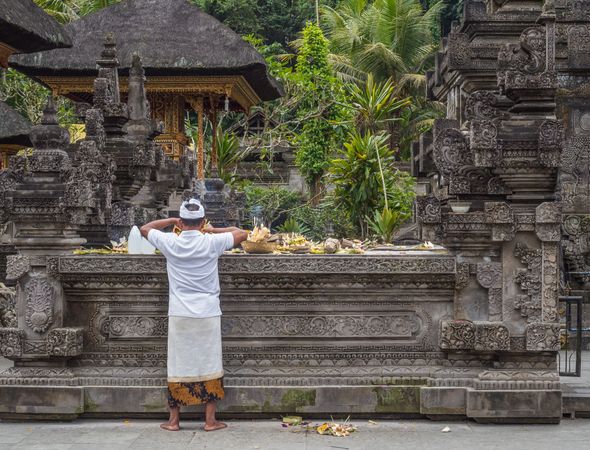 Bali, Indonesia - August, 15 2015: Anonymous man standing near table with religious gifts