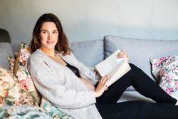 Pregnant woman reading a book on sofa
