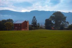 Green field and brick house near hills