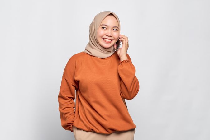 Smiling Muslim woman smiling with smart phone to her ear