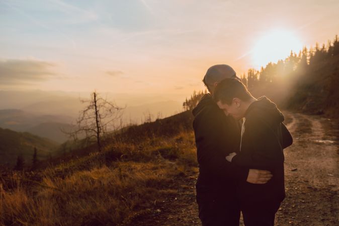 Men hugging and kissing in forest