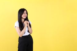 Young Asian Indonesian Woman Wearing White Shirt, Her Hands are Clasped in front of Her Chest.