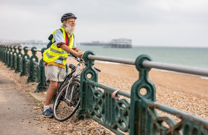 Smiling older man with bike looking at coastal view